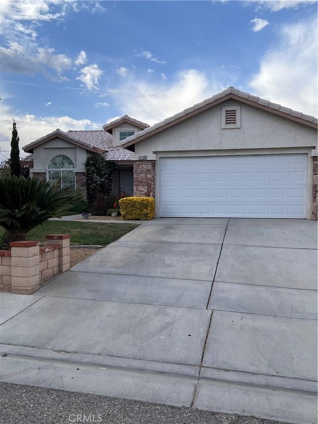 14106 Dartmouth St, Hesperia, CA 92344 - view of front of property with stucco siding, concrete driveway, a tiled roof, a garage, and stone siding
