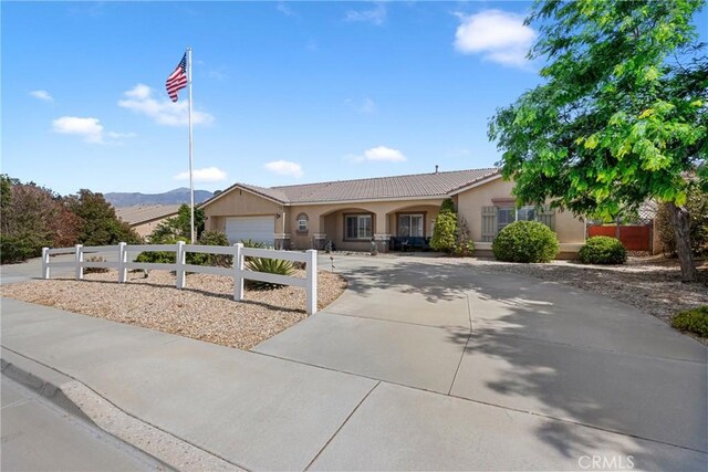 1410 Charles St, Banning, CA 92220 - ranch-style home with driveway, stucco siding, a garage, a tile roof, and a mountain view