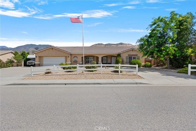 1410 Charles St, Banning, CA 92220 - ranch-style house with a fenced front yard, a mountain view, driveway, a tile roof, and stucco siding