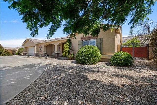 1410 Charles St, Banning, CA 92220 - view of front of home with a garage, driveway, stucco siding, and a tiled roof