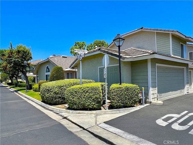 2014 W Hartford Pl Unit 58, Anaheim, CA 92801 - view of side of property featuring an attached garage, asphalt driveway, and stucco siding