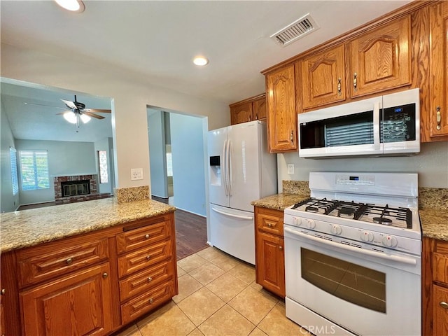 2014 W Hartford Pl Unit 58, Anaheim, CA 92801 - kitchen with white appliances, brown cabinets, a ceiling fan, light stone counters, and light tile patterned floors