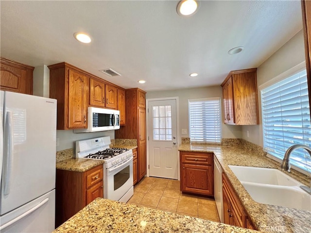 2014 W Hartford Pl Unit 58, Anaheim, CA 92801 - kitchen featuring white appliances, recessed lighting, light tile patterned floors, brown cabinetry, and light stone countertops