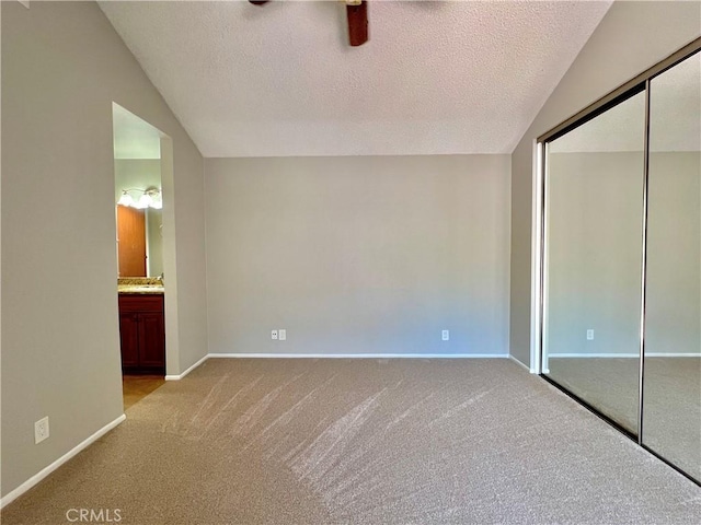 2014 W Hartford Pl Unit 58, Anaheim, CA 92801 - unfurnished bedroom with light colored carpet, a closet, a textured ceiling, lofted ceiling, and connected bathroom