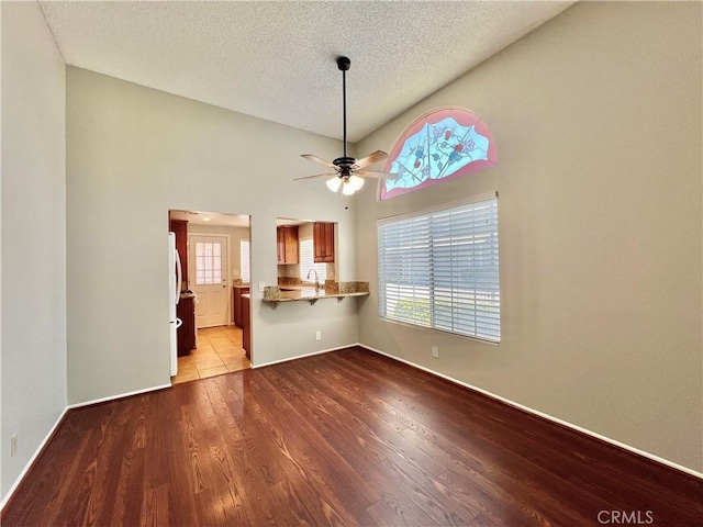 2014 W Hartford Pl Unit 58, Anaheim, CA 92801 - unfurnished living room featuring plenty of natural light, a ceiling fan, wood finished floors, a textured ceiling, and high vaulted ceiling