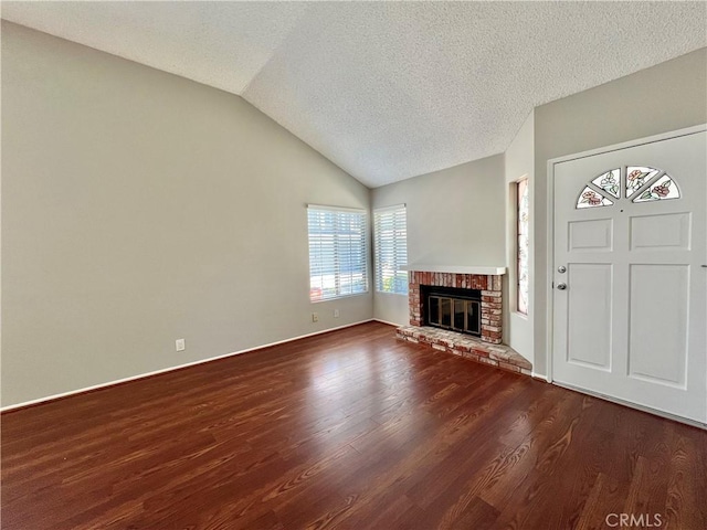 2014 W Hartford Pl Unit 58, Anaheim, CA 92801 - unfurnished living room with dark wood-style flooring, vaulted ceiling, a brick fireplace, and a textured ceiling
