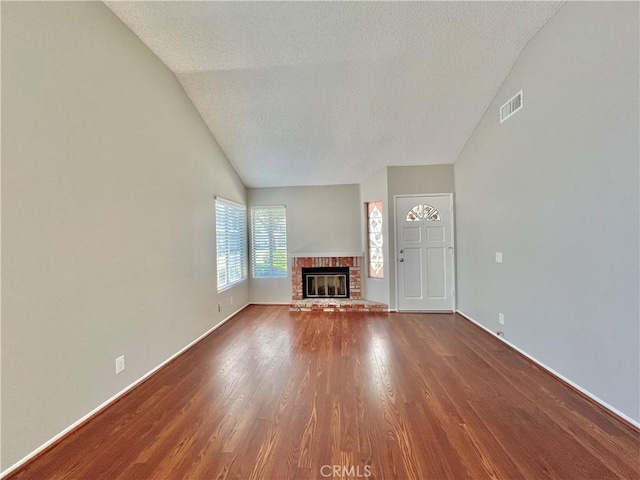 2014 W Hartford Pl Unit 58, Anaheim, CA 92801 - unfurnished living room featuring vaulted ceiling, dark wood-style floors, a brick fireplace, and a textured ceiling