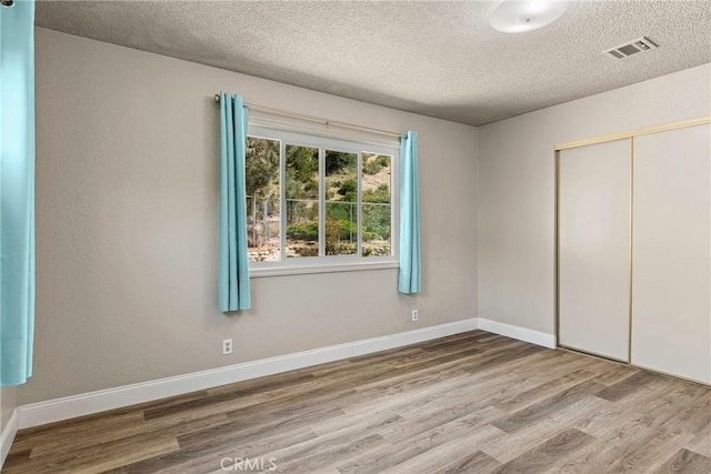 26865 Pine Canyon Rd, Lake Hughes, CA 93532 - unfurnished bedroom featuring wood finished floors, a textured ceiling, and a closet