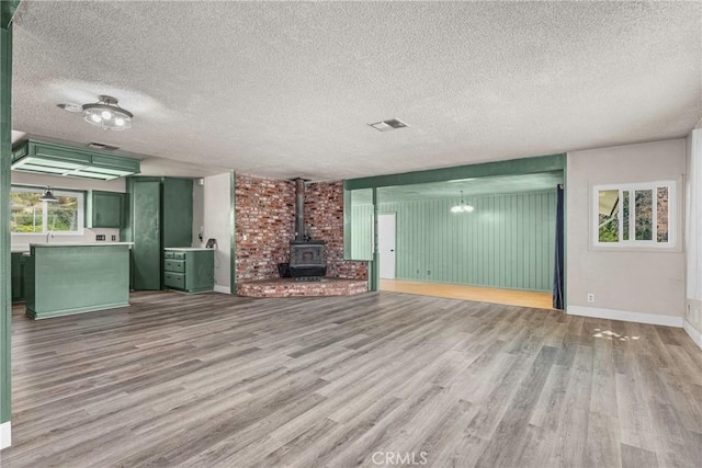 26865 Pine Canyon Rd, Lake Hughes, CA 93532 - unfurnished living room with wood finished floors, a wood stove, and a textured ceiling