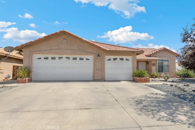 14389 Northstar Ave, Victorville, CA 92392 - mediterranean / spanish house with a garage, concrete driveway, a tile roof, and stucco siding