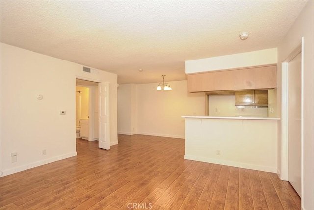 12601 Van Nuys Blvd Unit 103, Pacoima, CA 91331 - unfurnished living room with a chandelier, light wood-type flooring, and a textured ceiling