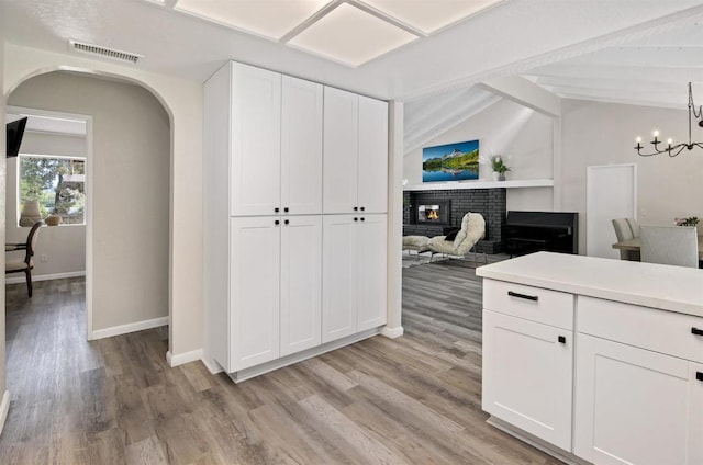 834 Cole Ranch Rd, Encinitas, CA 92024 - kitchen with a brick fireplace, arched walkways, light wood finished floors, and white cabinets