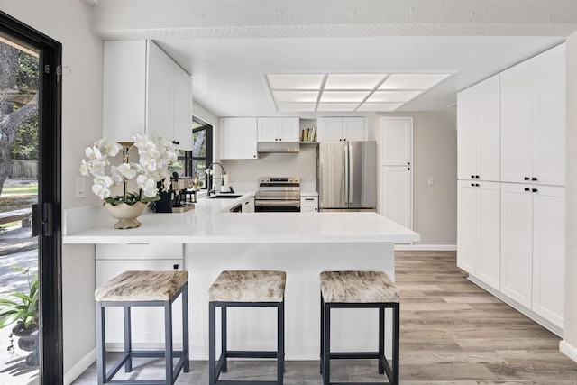 834 Cole Ranch Rd, Encinitas, CA 92024 - kitchen featuring stainless steel appliances, under cabinet range hood, a peninsula, and a kitchen bar