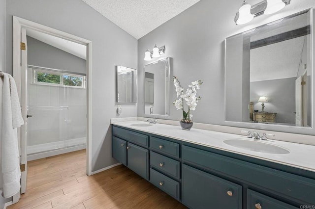 3551 Starboard Cir, Oceanside, CA 92054 - bathroom with double vanity, a textured ceiling, wood finished floors, lofted ceiling, and a shower