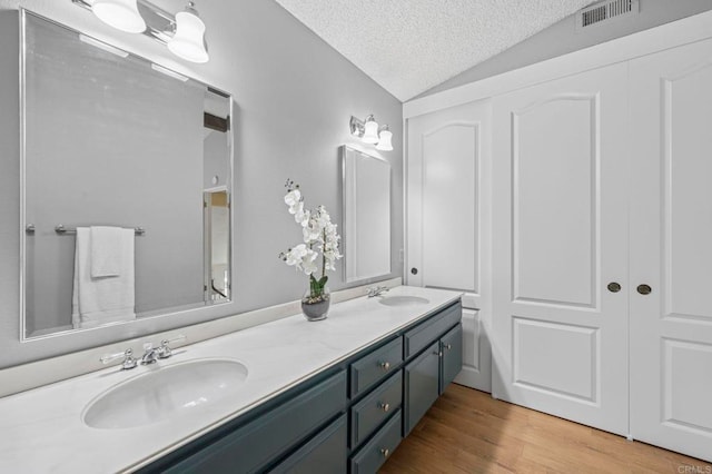 3551 Starboard Cir, Oceanside, CA 92054 - bathroom featuring double vanity, a textured ceiling, lofted ceiling, and wood finished floors