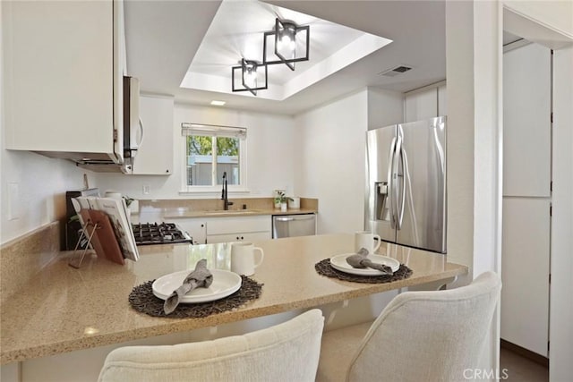 4440 Eagle Peak Rd Unit A, Concord, CA 94521 - kitchen with appliances with stainless steel finishes, a tray ceiling, a peninsula, white cabinets, and a breakfast bar