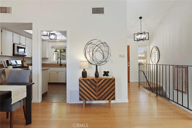 4440 Eagle Peak Rd Unit A, Concord, CA 94521 - interior space featuring stainless steel microwave, a chandelier, white cabinetry, light wood-style floors, and a towering ceiling