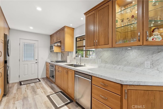 3654 4th Ave, La Crescenta, CA 91214 - kitchen featuring appliances with stainless steel finishes, stacked washer and clothes dryer, brown cabinets, light wood-type flooring, and light countertops