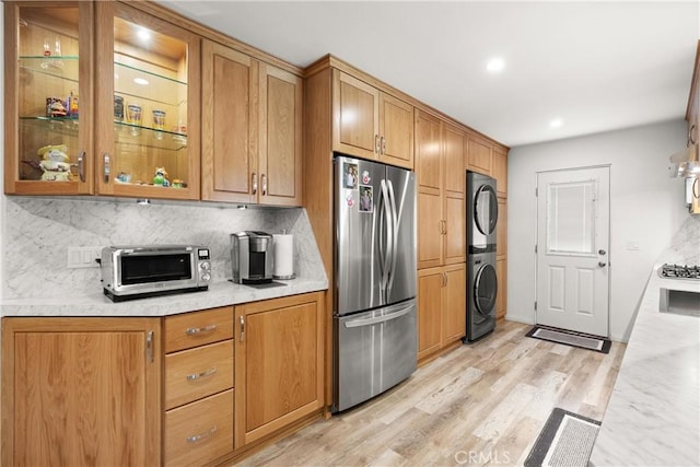 3654 4th Ave, La Crescenta, CA 91214 - kitchen featuring freestanding refrigerator, estacked washer and dryer, backsplash, glass insert cabinets, and light wood-style floors