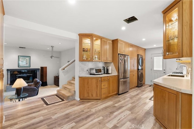 3654 4th Ave, La Crescenta, CA 91214 - kitchen featuring freestanding refrigerator, stacked washer / drying machine, light wood-style flooring, light countertops, and backsplash