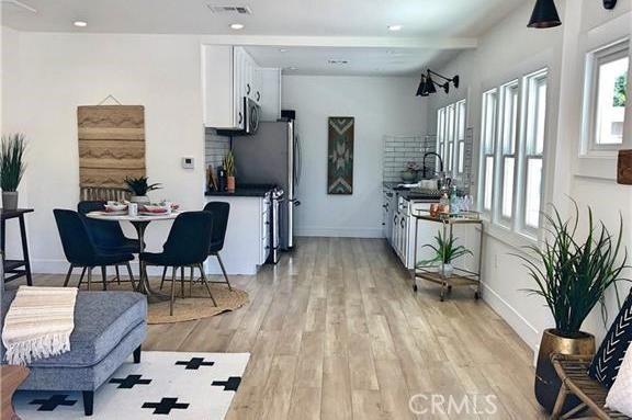 341 W Whiting Ave W, Fullerton, CA 92832 - kitchen with white cabinetry, light wood-style floors, dark countertops, and stainless steel microwave