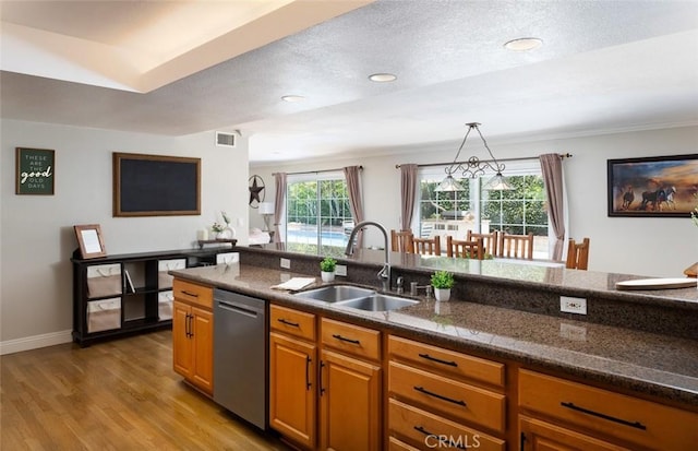 18921 Silver Maple Way N, Tustin, CA 92705 - kitchen with stainless steel dishwasher, light wood-type flooring, brown cabinets, dark stone counters, and hanging light fixtures