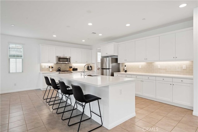 421 Azalea St, Fillmore, CA 93015 - kitchen with stainless steel appliances, a breakfast bar area, light tile patterned flooring, tasteful backsplash, and a center island with sink