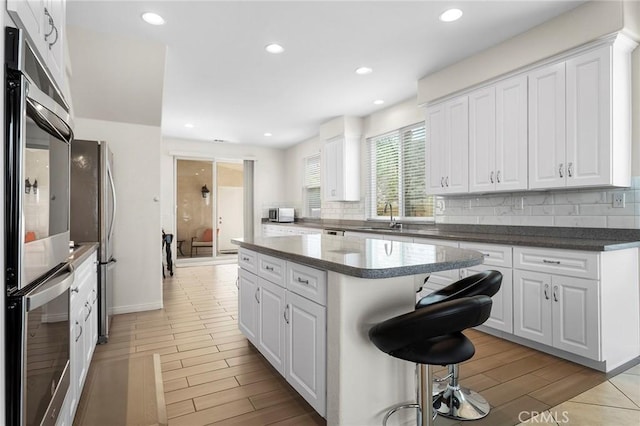 25 Vista Palermo, Lake Elsinore, CA 92532 - kitchen featuring tasteful backsplash, a kitchen island, wood finish floors, white cabinets, and recessed lighting