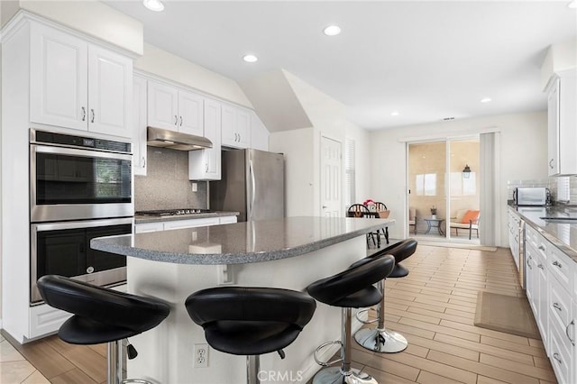 25 Vista Palermo, Lake Elsinore, CA 92532 - kitchen with stainless steel appliances, under cabinet range hood, a breakfast bar, tasteful backsplash, and recessed lighting