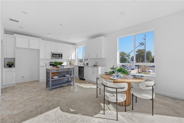 94191/2 N Sepulveda Blvd Unit 1, North Hills, CA 91343 - kitchen featuring appliances with stainless steel finishes, white cabinetry, a center island, light countertops, and open shelves