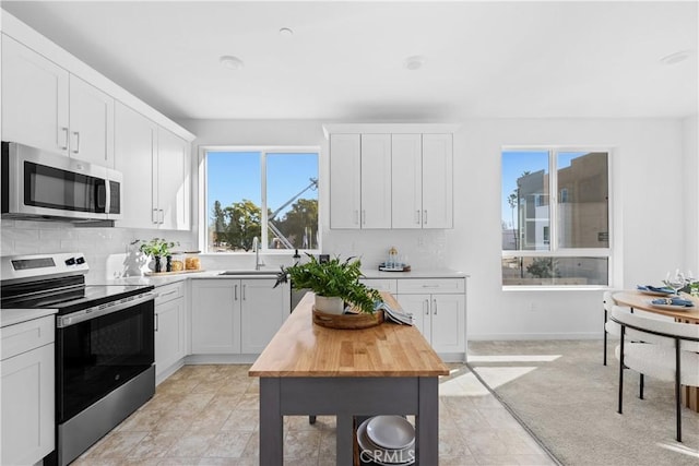 94191/2 N Sepulveda Blvd Unit 1, North Hills, CA 91343 - kitchen with stainless steel appliances, butcher block countertops, tasteful backsplash, and white cabinetry