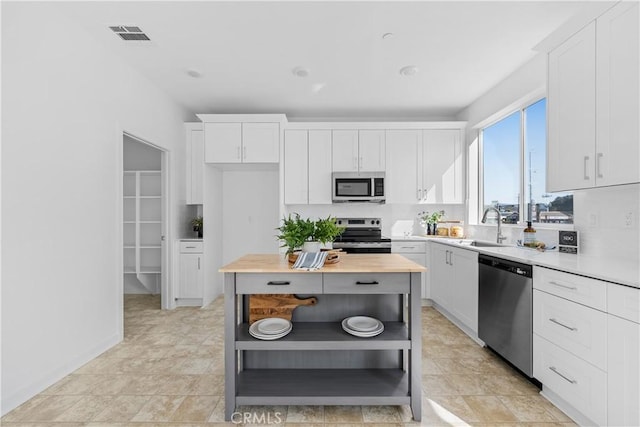 94191/2 N Sepulveda Blvd Unit 1, North Hills, CA 91343 - kitchen with stainless steel appliances, open shelves, white cabinets, wood counters, and a center island