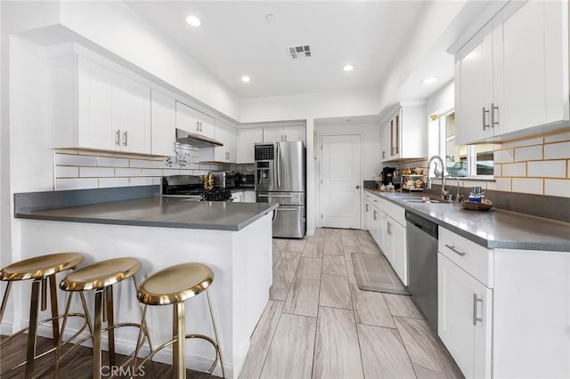 418 N Dalton Ave, Azusa, CA 91702 - kitchen with stainless steel appliances, under cabinet range hood, a peninsula, dark countertops, and recessed lighting