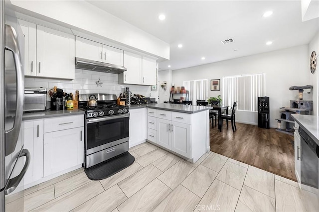 418 N Dalton Ave, Azusa, CA 91702 - kitchen featuring stainless steel appliances, a peninsula, under cabinet range hood, dark countertops, and white cabinetry