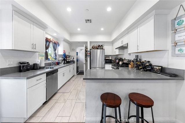 418 N Dalton Ave, Azusa, CA 91702 - kitchen with appliances with stainless steel finishes, a peninsula, backsplash, under cabinet range hood, and white cabinetry