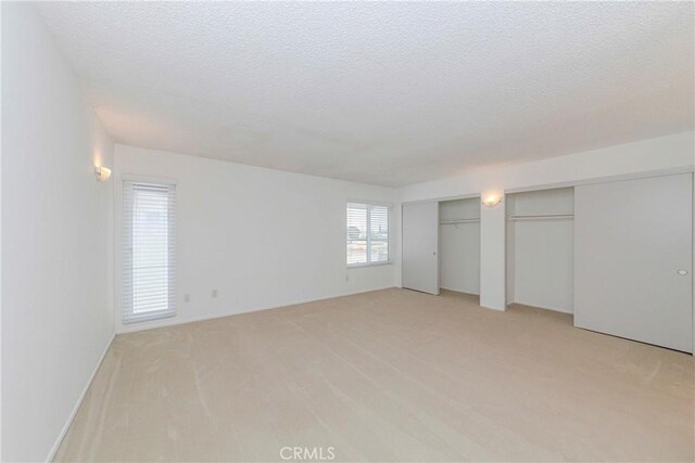 2406 Descanso Way, Torrance, CA 90504 - unfurnished bedroom featuring multiple closets, light colored carpet, and a textured ceiling