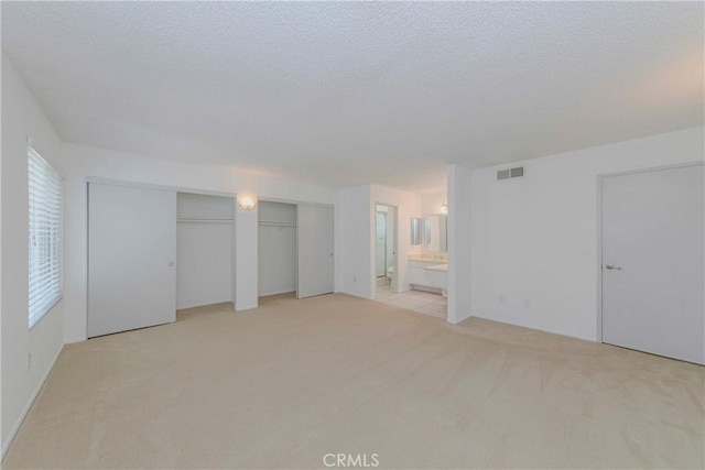 2406 Descanso Way, Torrance, CA 90504 - unfurnished bedroom featuring light colored carpet, multiple closets, a textured ceiling, and ensuite bathroom