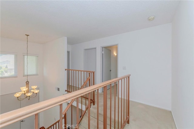 2406 Descanso Way, Torrance, CA 90504 - hallway with an upstairs landing, a chandelier, light colored carpet, and a textured ceiling