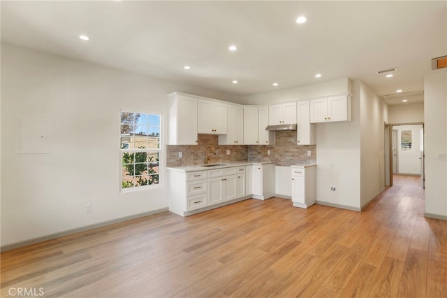 1241 W 22nd St, Los Angeles, CA 90007 - kitchen featuring light wood-style floors, tasteful backsplash, under cabinet range hood, white cabinets, and recessed lighting