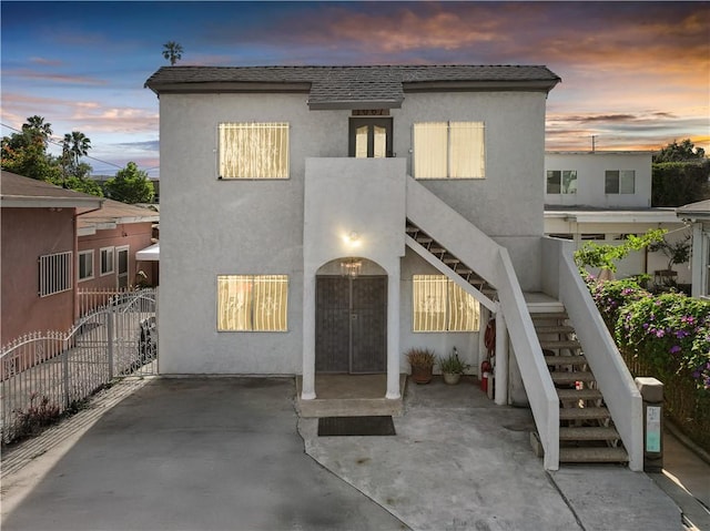 1067 N Wilton Pl, Los Angeles, CA 90038 - view of front of home with stairway, stucco siding, roof with shingles, and a patio area