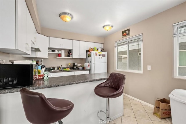 34055 Silver Lantern St, Dana Point, CA 92629 - kitchen featuring freestanding refrigerator, black microwave, a peninsula, white cabinets, and a breakfast bar area