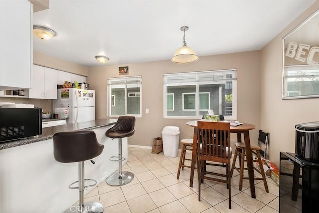 34055 Silver Lantern St, Dana Point, CA 92629 - kitchen featuring freestanding refrigerator, black microwave, white cabinetry, dark countertops, and pendant lighting