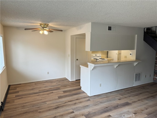 3078 Winfield Ave, La Verne, CA 91750 - kitchen with electric stove, wood finished floors, a textured ceiling, a kitchen bar, and a peninsula