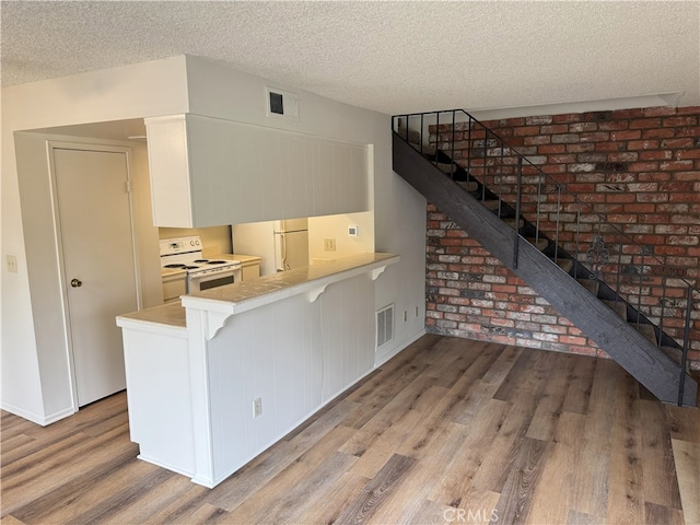 3078 Winfield Ave, La Verne, CA 91750 - kitchen with white appliances, wood finished floors, a textured ceiling, a peninsula, and light countertops