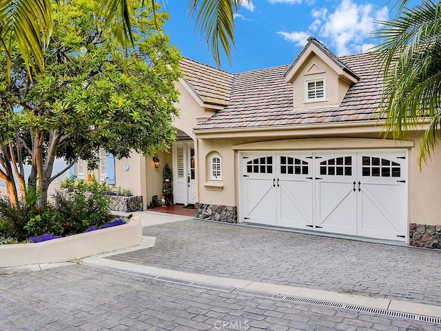 12272 Media Panorama, North Tustin, CA 92705 - view of front of home featuring stucco siding, decorative driveway, a garage, and stone siding
