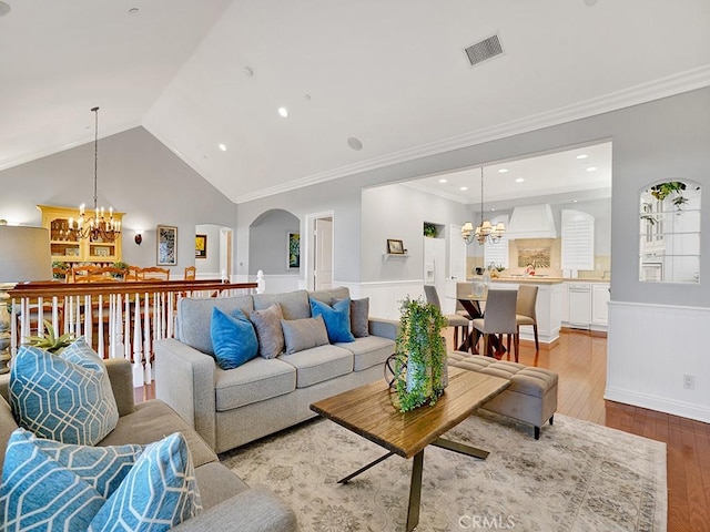 12272 Media Panorama, North Tustin, CA 92705 - living room featuring a chandelier, light wood-style floors, a wainscoted wall, arched walkways, and vaulted ceiling
