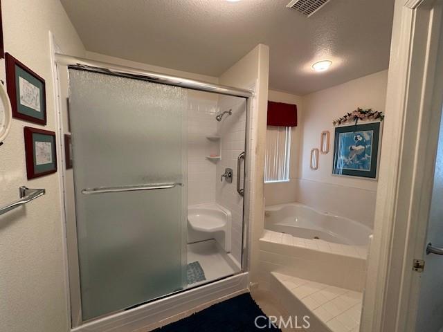 3854 Canvasback Ct, Merced, CA 95340 - bathroom featuring a bath, a shower stall, and a textured ceiling
