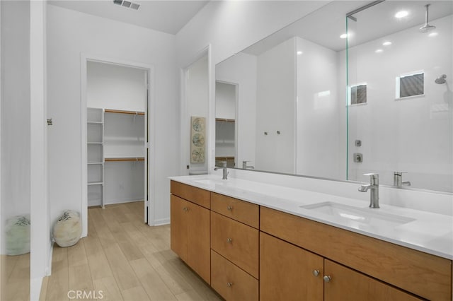 11937 Wandering Way, Corona, CA 92883 - bathroom featuring a walk in closet, double vanity, wood finished floors, walk in shower, and recessed lighting
