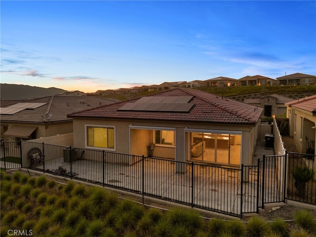 11937 Wandering Way, Corona, CA 92883 - rear view of house featuring a tile roof, solar panels, stucco siding, and a fenced backyard