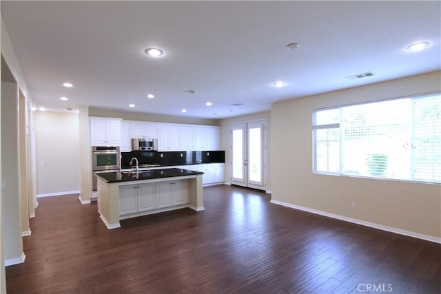 629 E Gardenia Dr, Azusa, CA 91702 - kitchen featuring appliances with stainless steel finishes, a kitchen island with sink, dark countertops, dark wood-style floors, and recessed lighting